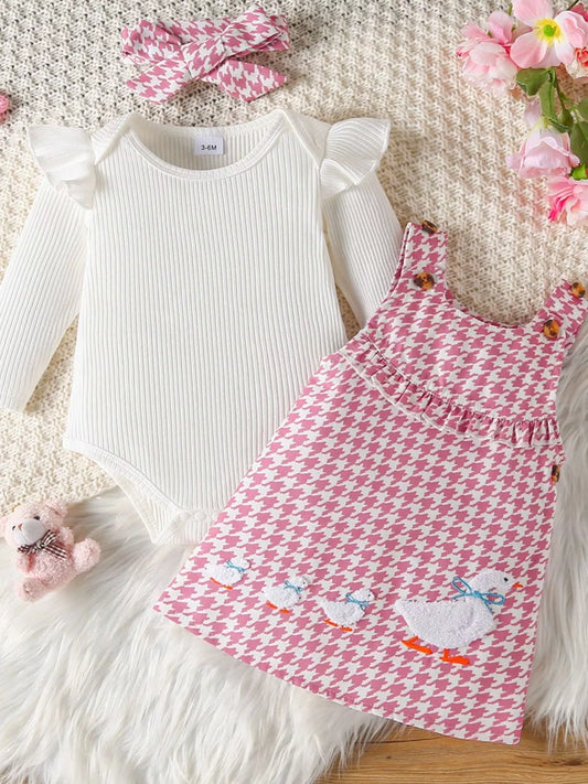 Pink houndstooth baby jumper dress with embroidered duck family and a white ruffle long-sleeve onesie, displayed with matching bow and plush toy.