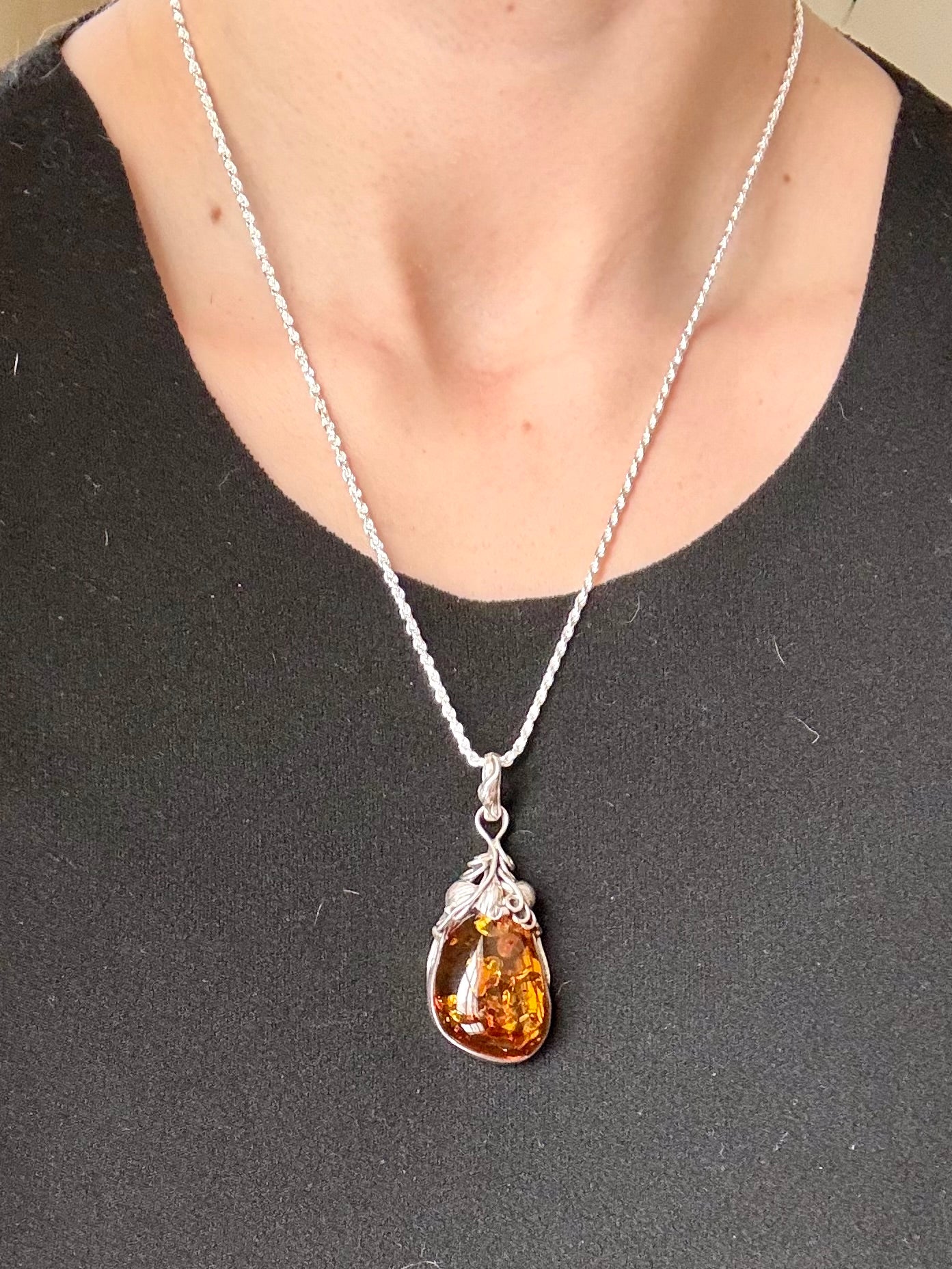 Necklace with a teardrop-shaped amber pendant on a plain background