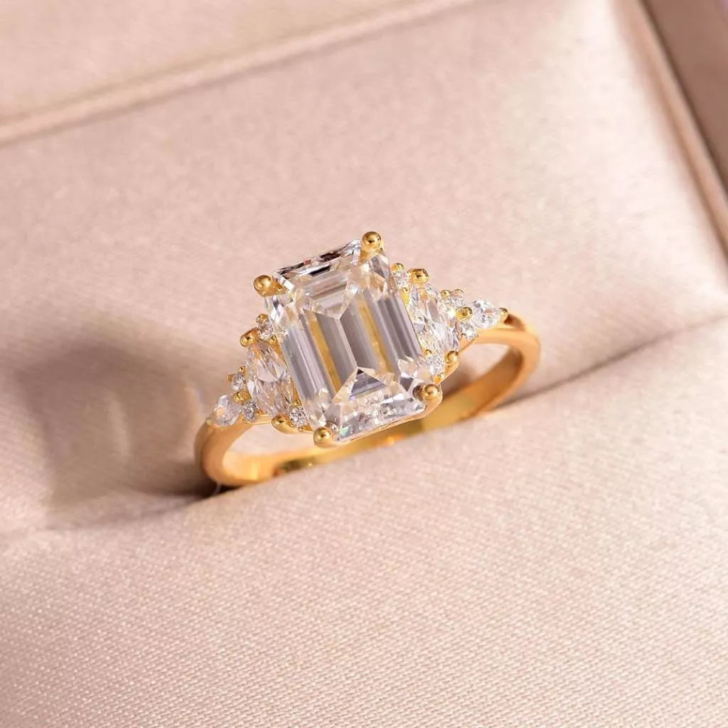 Close-up of emerald-cut moissanite ring with gold band and zircon accents — luxurious and elegant engagement ring from A Whimsical Affair.