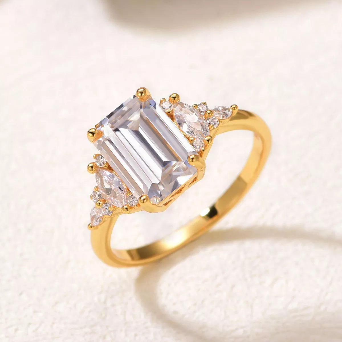 Close-up of emerald-cut moissanite ring with gold band and zircon accents — luxurious and elegant engagement ring from A Whimsical Affair.