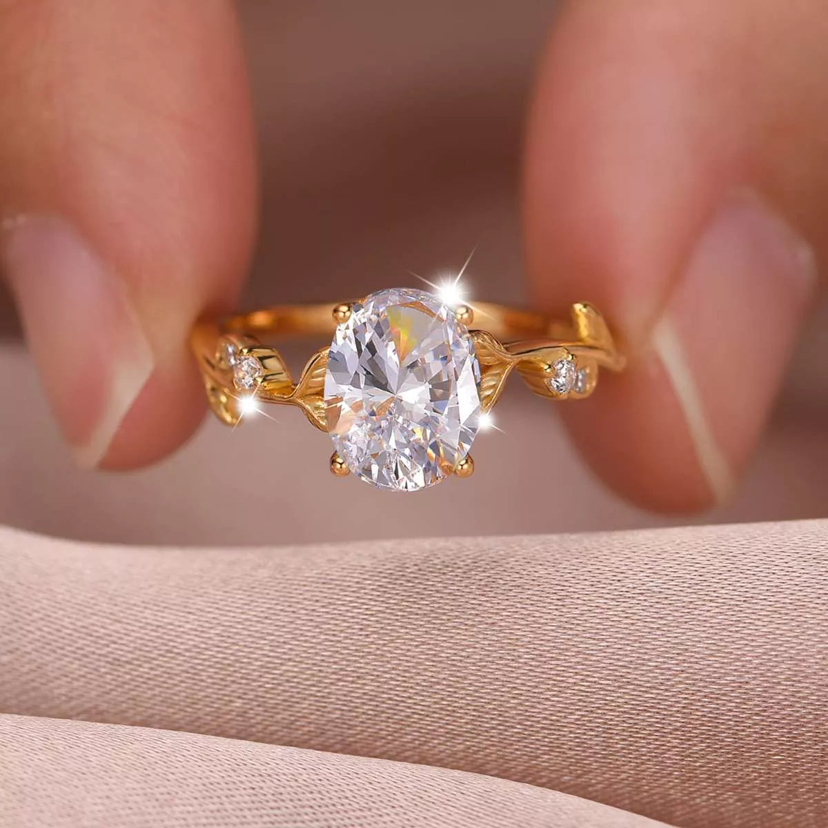 Gold oval moissanite ring with vine-like band and small zircon accents displayed in a blush jewelry box.