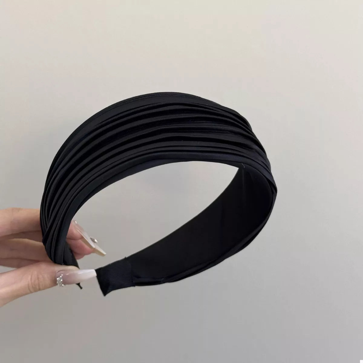 Woman holding the Everyday Elegance Pleated Headband in Black