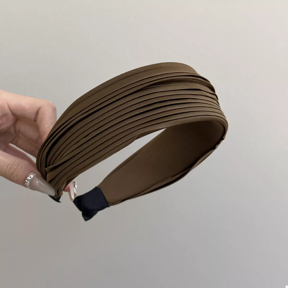 Woman holding the Everyday Elegance Pleated Headband in Black