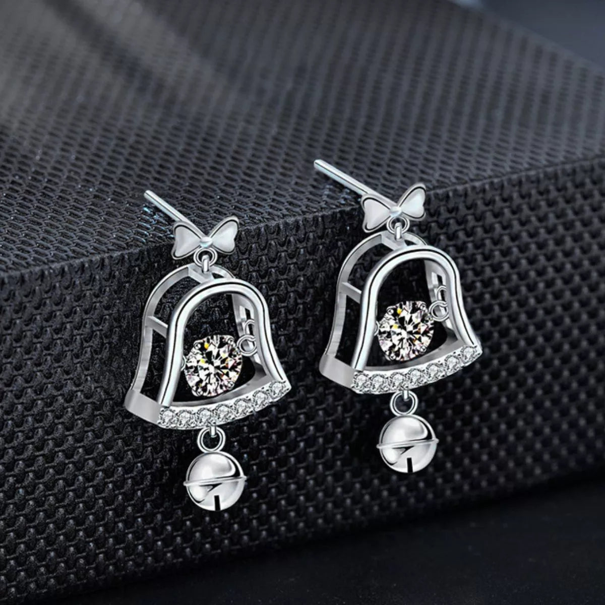 Pair of platinum-plated sterling silver bell earrings with 0.5ct moissanite center stones and dangling jingle bells.