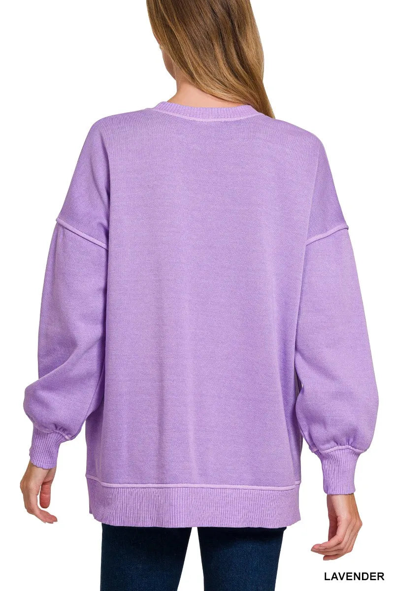 Woman wearing an oversized lavender pullover sweatshirt with contrast white stitching and balloon sleeves.