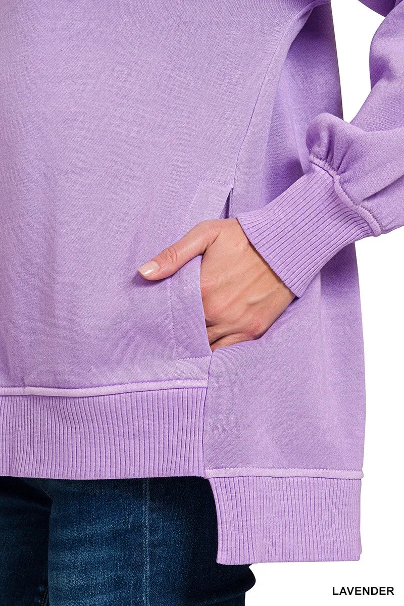 Woman wearing an oversized lavender pullover sweatshirt with contrast white stitching and balloon sleeves.