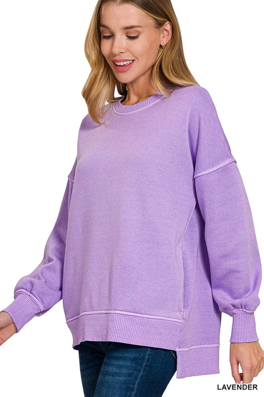 Woman wearing an oversized lavender pullover sweatshirt with contrast white stitching and balloon sleeves.