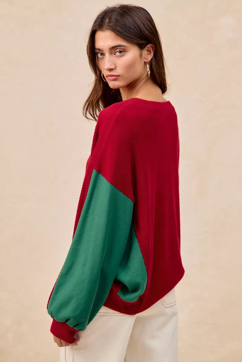 Woman wearing a red Christmas sweater with embroidered green tree designs and contrasting green sleeves.