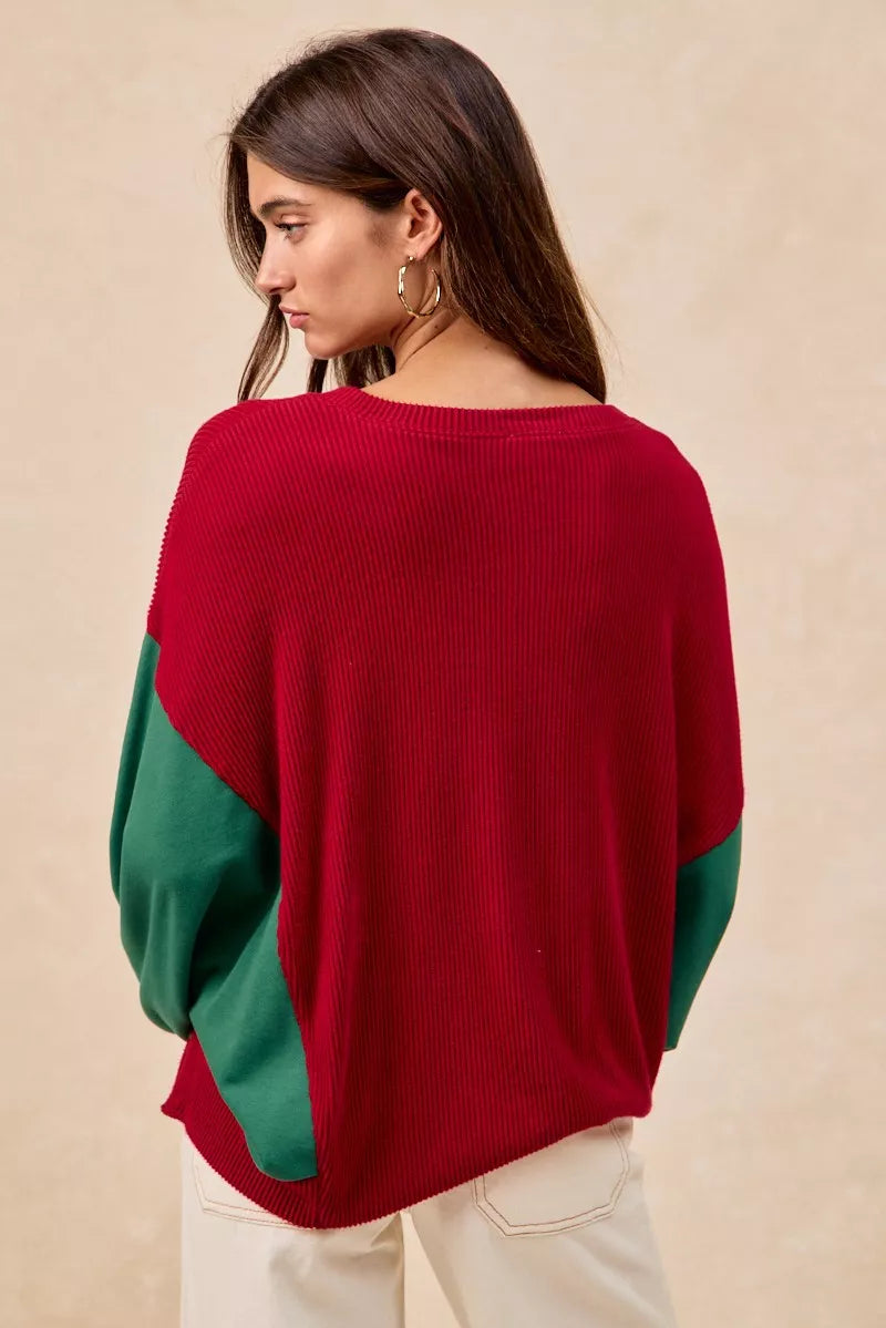 Woman wearing a red Christmas sweater with embroidered green tree designs and contrasting green sleeves.