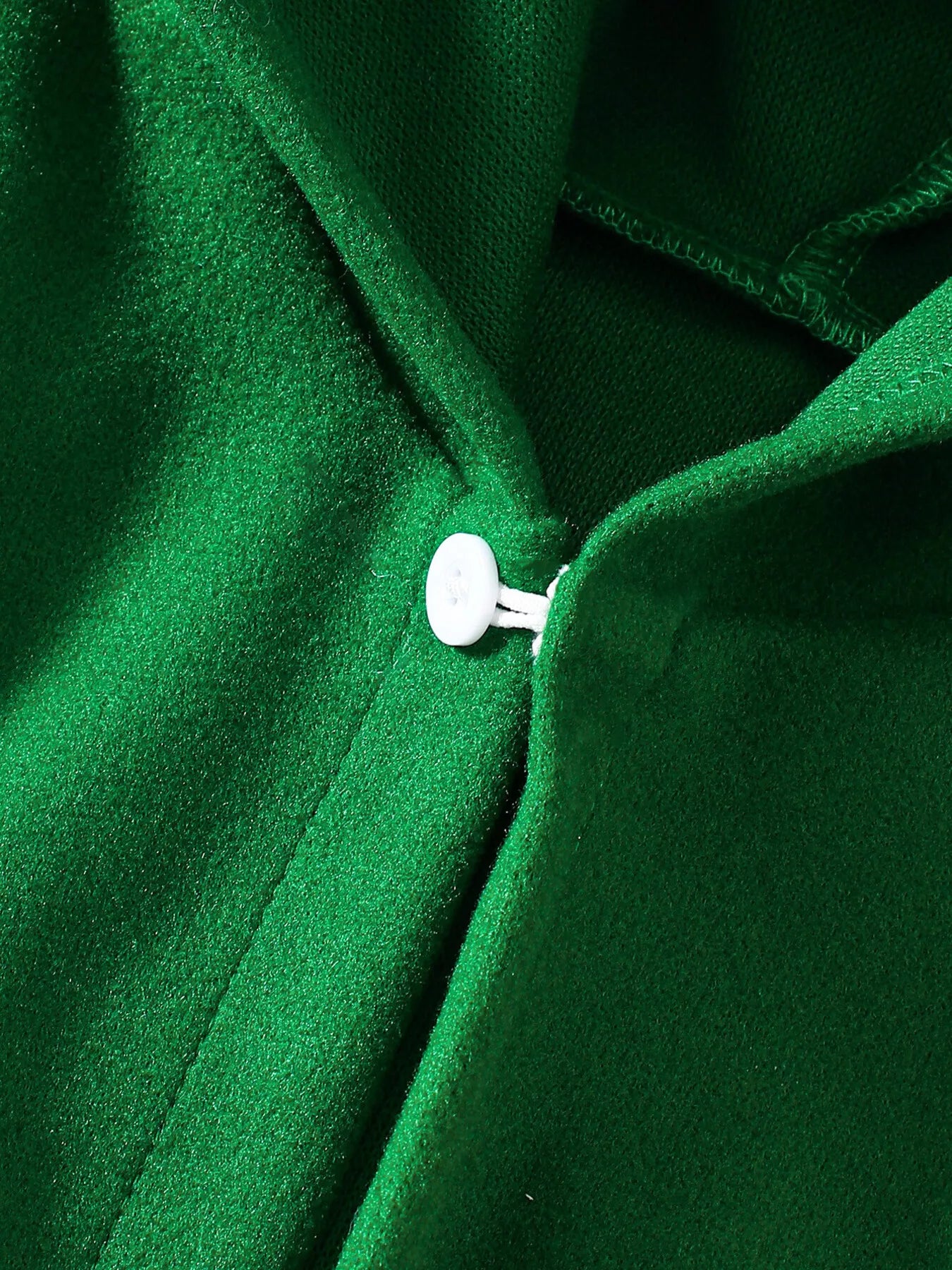 Green Christmas hooded cape for kids with “MERRY” embroidery and reindeer appliqués, pom-trim hem, displayed on holiday background.