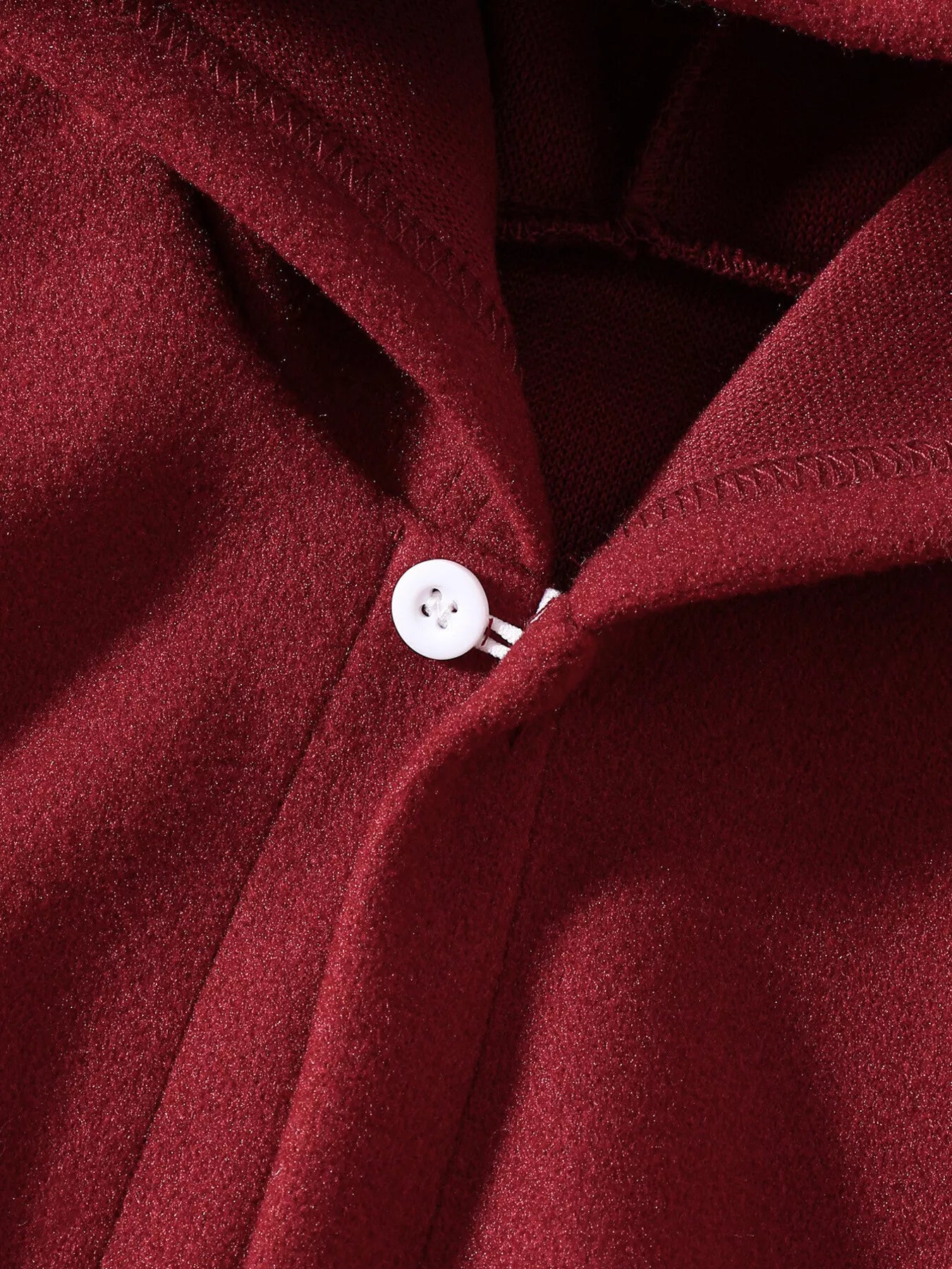 Red Christmas hooded cape for kids with “MERRY” embroidery and reindeer appliqués, pom-trim hem, displayed on holiday background.