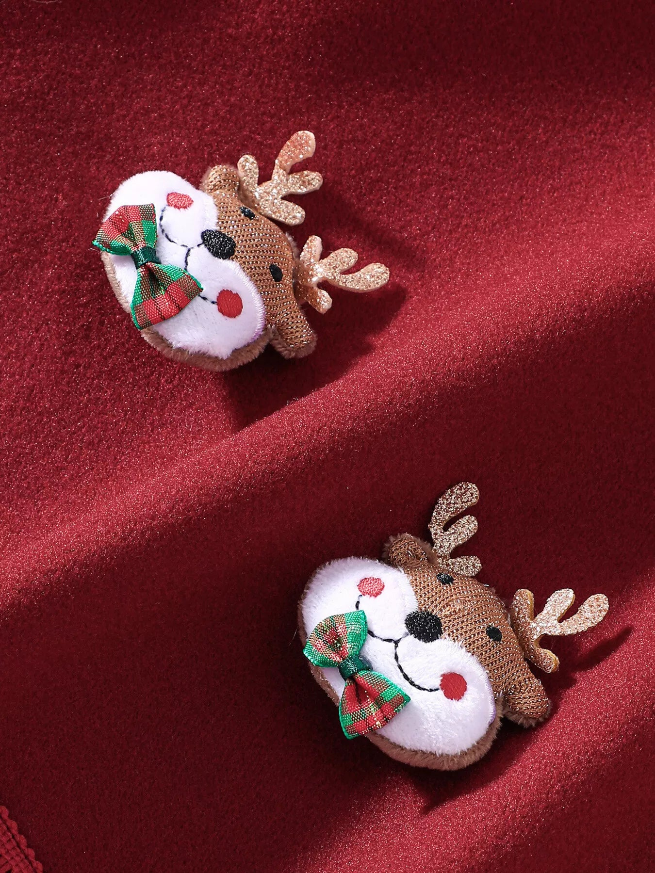 Red Christmas hooded cape for kids with “MERRY” embroidery and reindeer appliqués, pom-trim hem, displayed on holiday background.