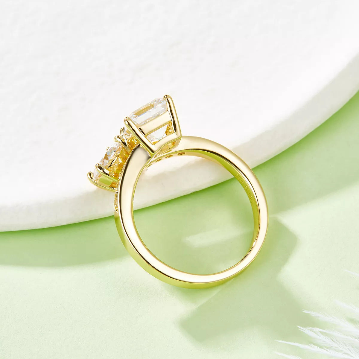 Gold-plated bypass ring with round and square moissanite stones on a light background
