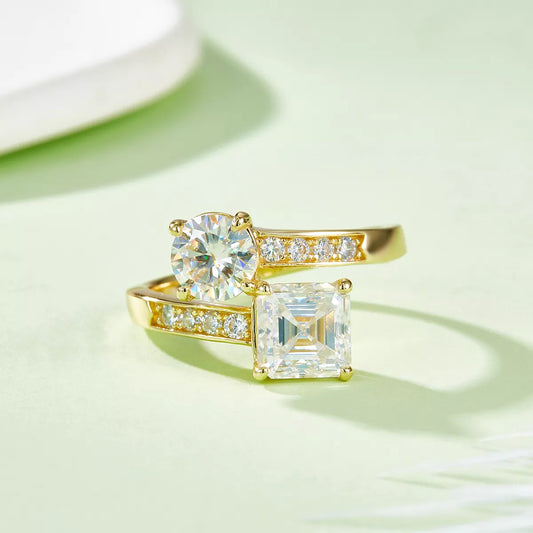 Gold-plated bypass ring with round and square moissanite stones on a light background