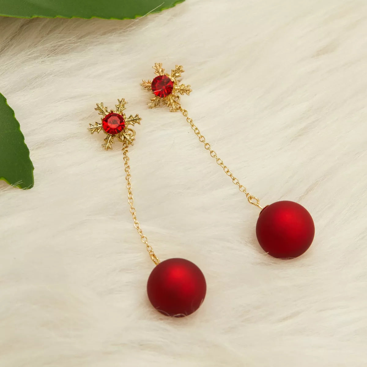 Festive red bauble drop earrings with snowflake studs and gold chain detailing.