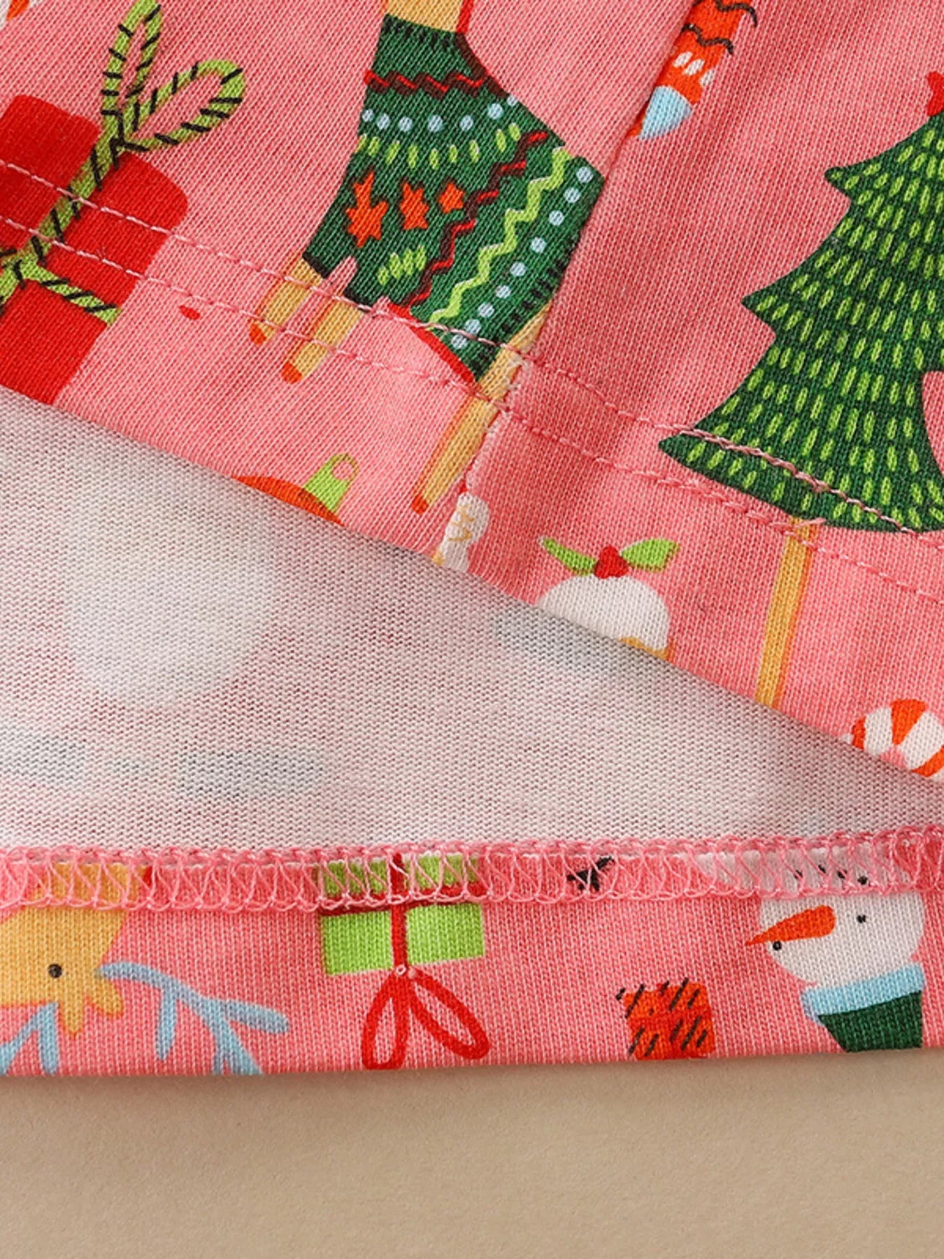 Pink Christmas-themed kids dress with Santa, reindeer, snowmen, gifts, gingerbread men, and ornaments printed all over.
