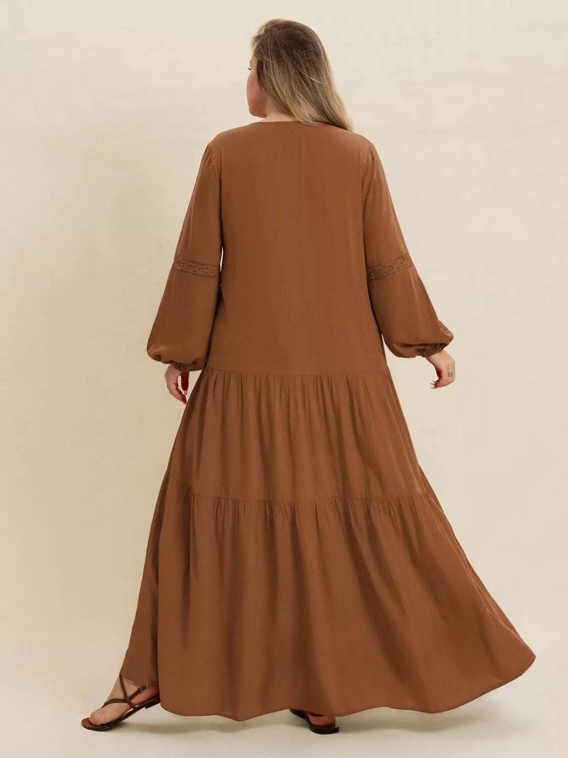 Woman wearing a camel-colored tiered maxi dress with lace detail and long sleeves — elegant flowing boho dress from A Whimsical Affair.