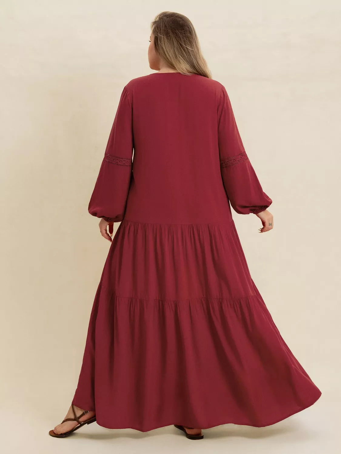 Woman wearing a burgundy-colored tiered maxi dress with lace detail and long sleeves — elegant flowing boho dress from A Whimsical Affair.