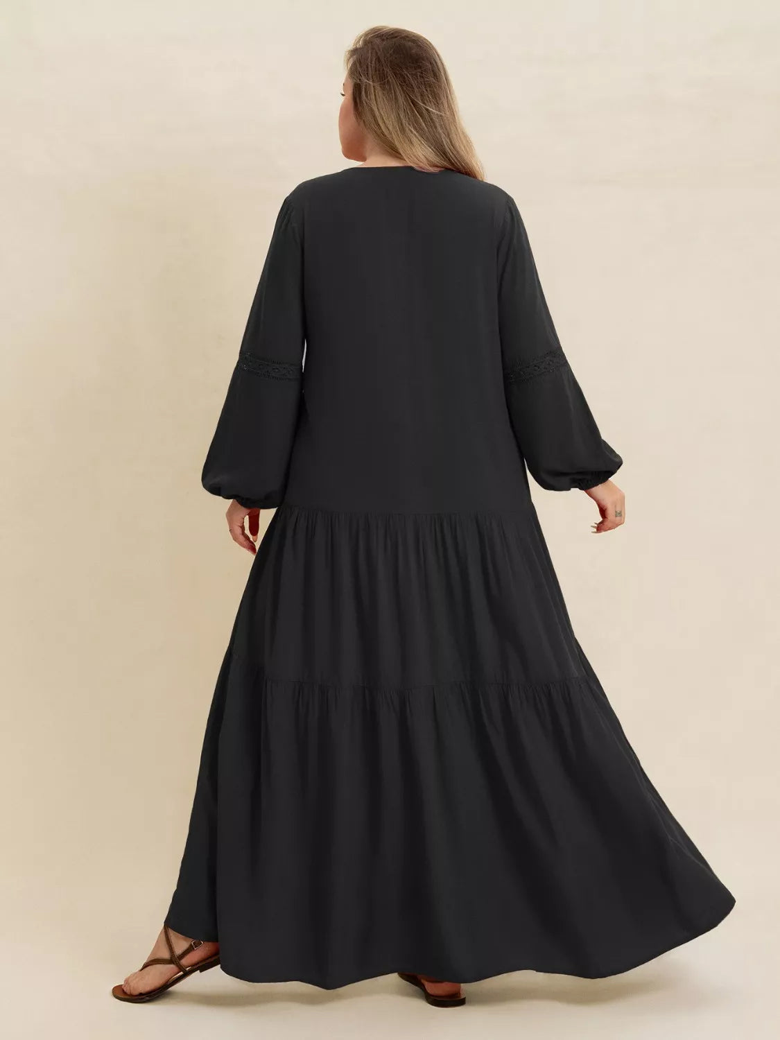 Woman wearing a black-colored tiered maxi dress with lace detail and long sleeves — elegant flowing boho dress from A Whimsical Affair.