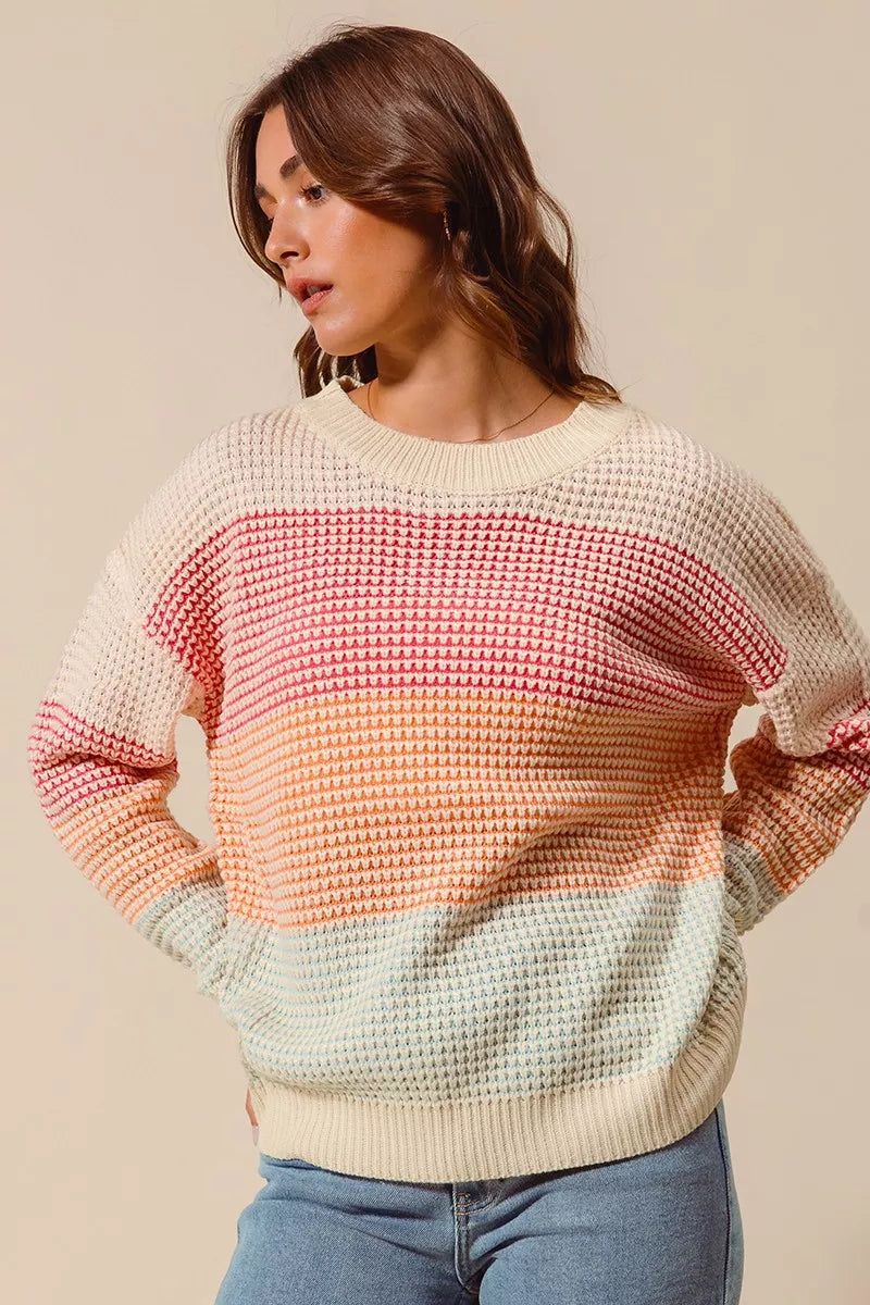 Woman wearing a pastel color block waffle-knit sweater in pink, orange, and blue tones — cozy ribbed pullover from A Whimsical Affair.
