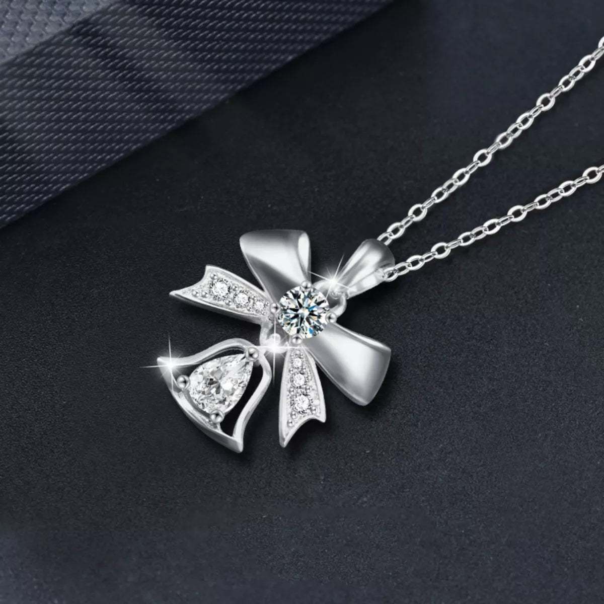 Close-up of Twinkling Holiday Bow Bell Moissanite Necklace with 0.5ct stone and delicate chain.
