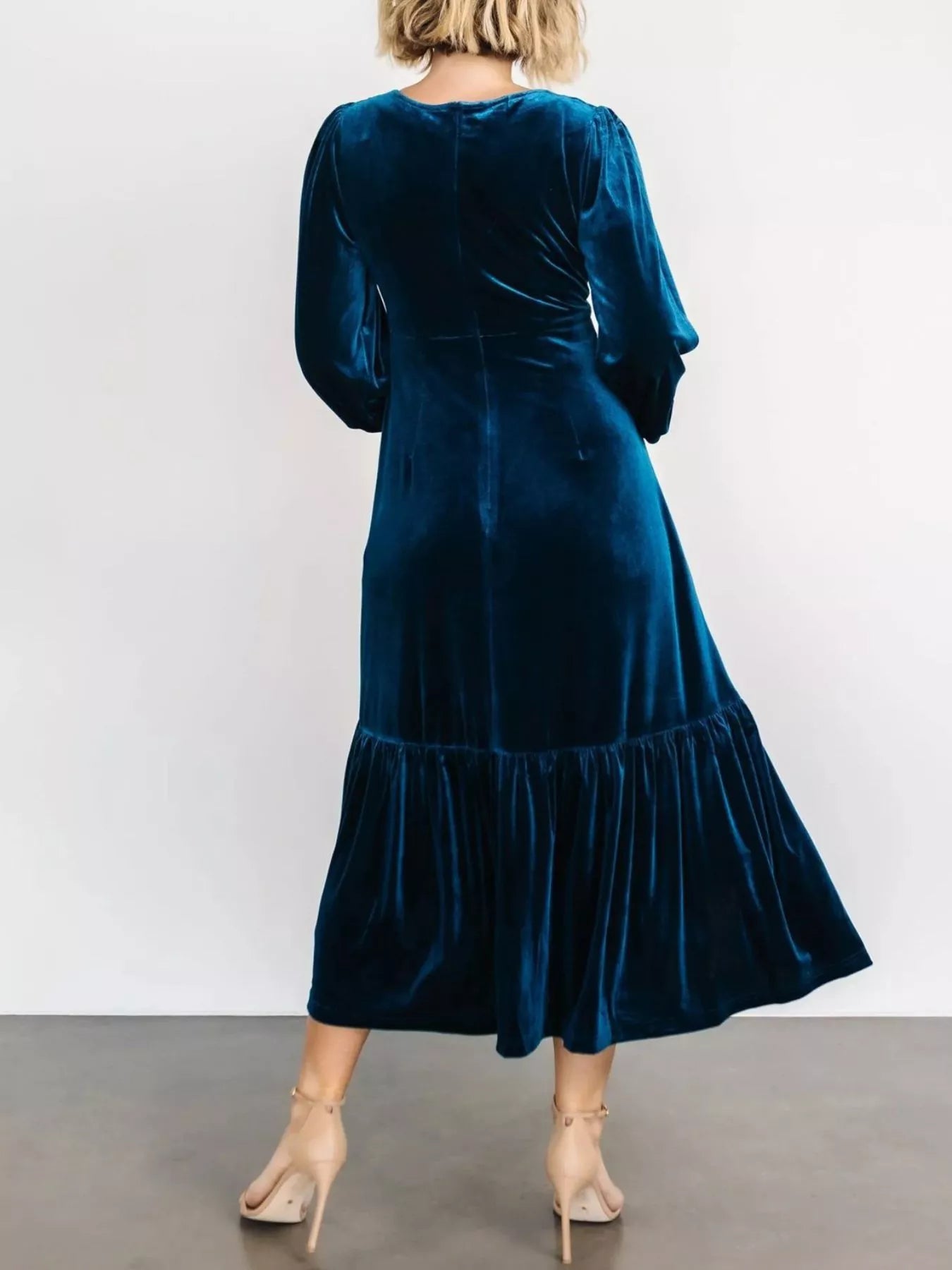 Woman wearing a dark blue velvet midi dress with long sleeves and tiered hem — elegant soft-touch holiday dress from A Whimsical Affair.