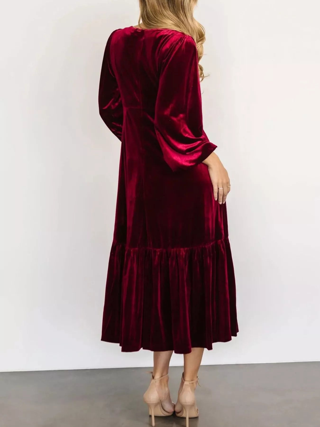 Woman wearing a red velvet midi dress with long sleeves and tiered hem — elegant soft-touch holiday dress from A Whimsical Affair.