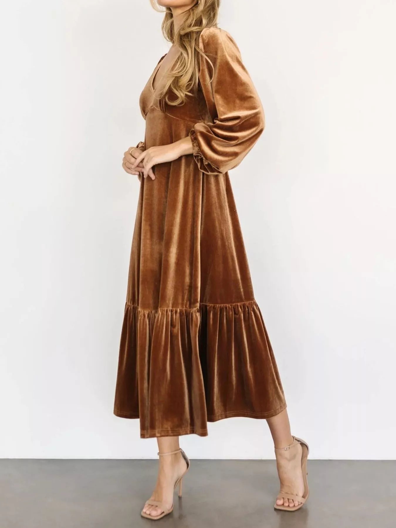 Woman wearing a gold velvet midi dress with long sleeves and tiered hem — elegant soft-touch holiday dress from A Whimsical Affair.