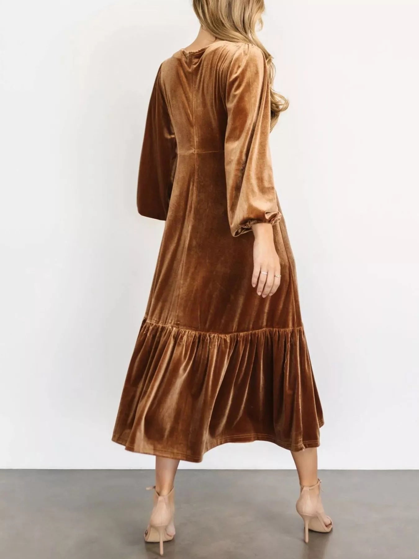 Woman wearing a gold velvet midi dress with long sleeves and tiered hem — elegant soft-touch holiday dress from A Whimsical Affair.