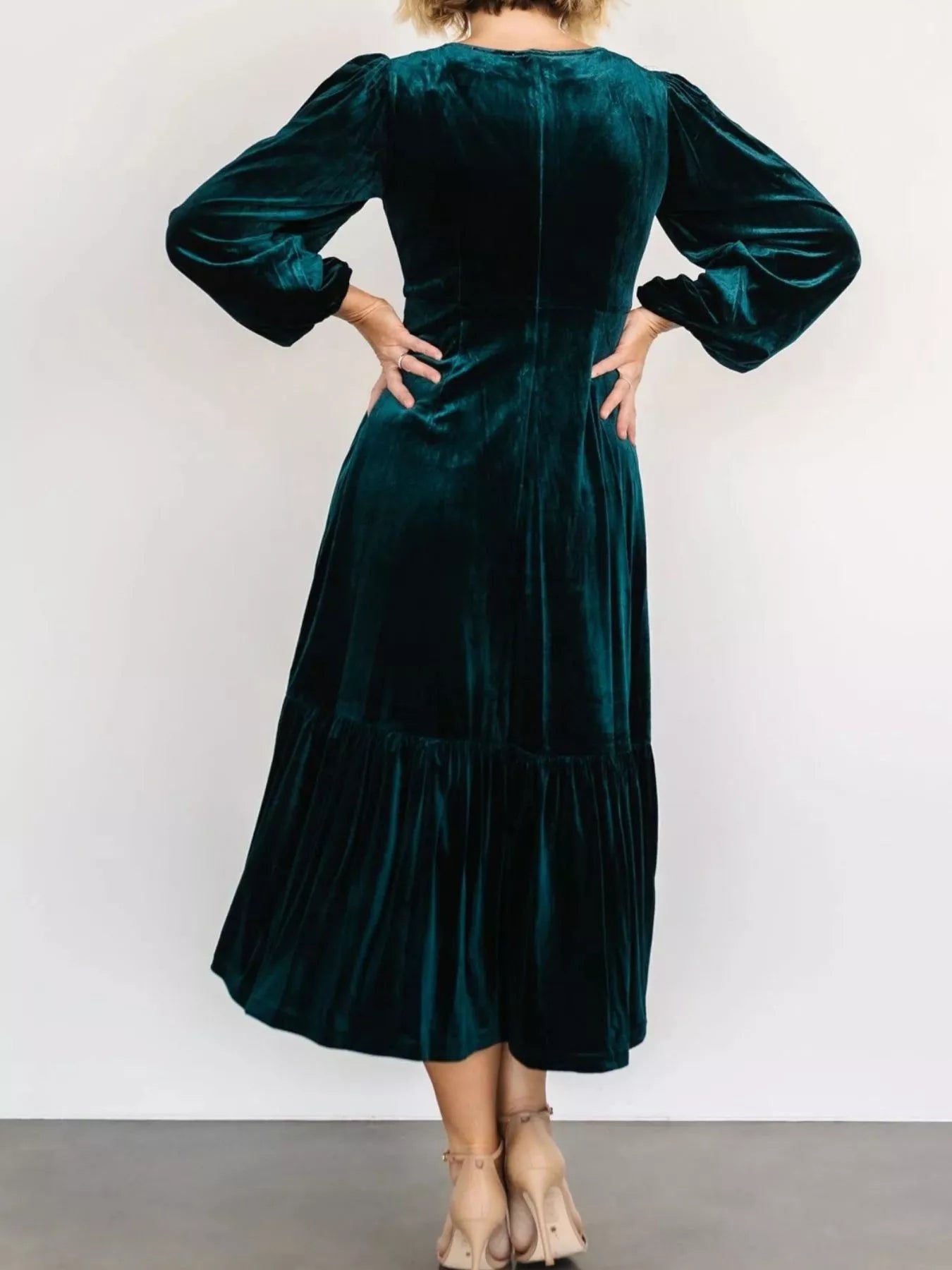 Woman wearing a peacock blue velvet midi dress with long sleeves and tiered hem — elegant soft-touch holiday dress from A Whimsical Affair.
