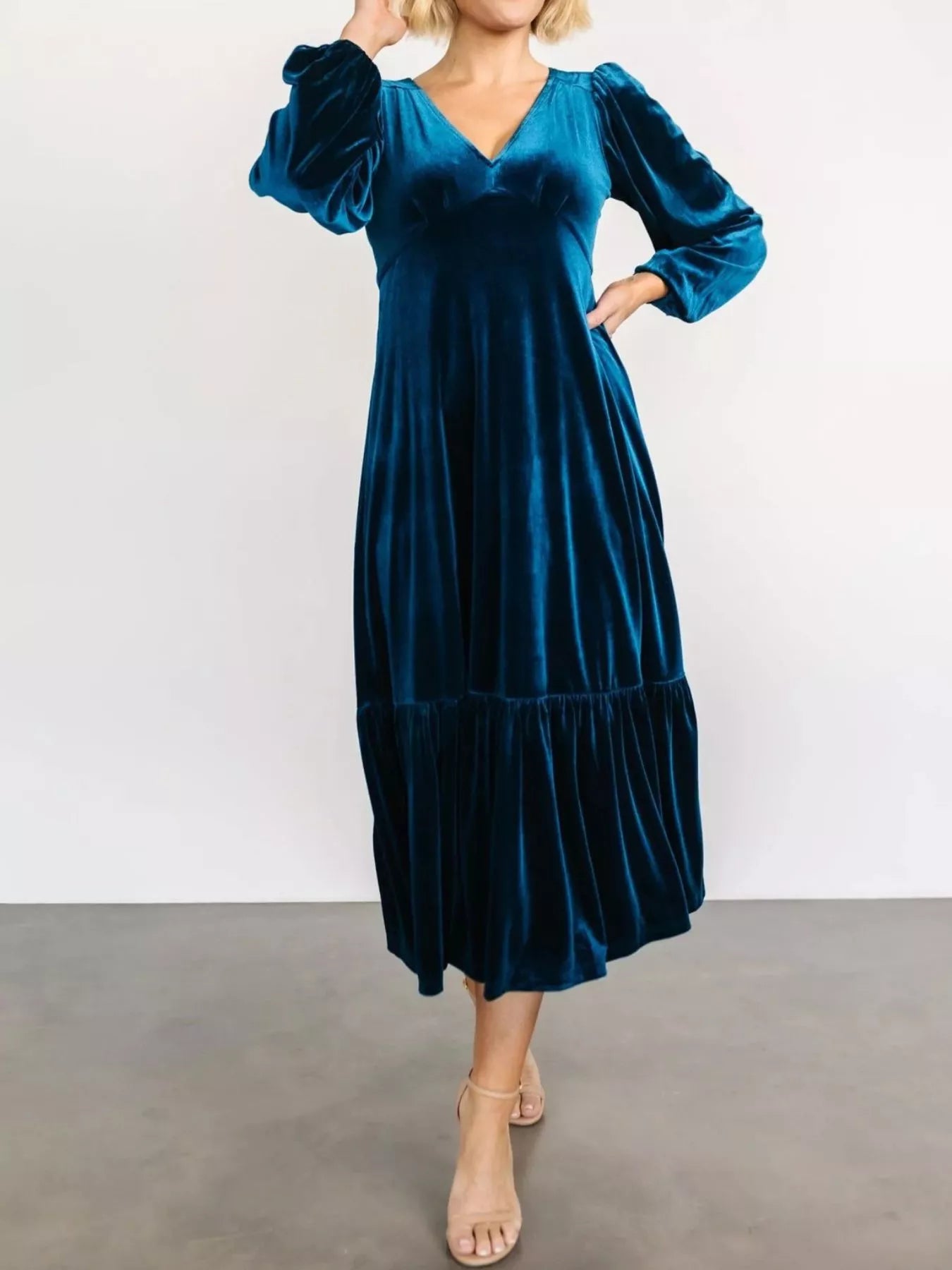 Woman wearing a dark blue velvet midi dress with long sleeves and tiered hem — elegant soft-touch holiday dress from A Whimsical Affair.