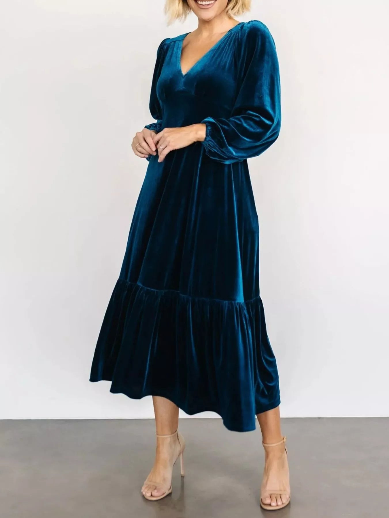 Woman wearing a dark blue velvet midi dress with long sleeves and tiered hem — elegant soft-touch holiday dress from A Whimsical Affair.