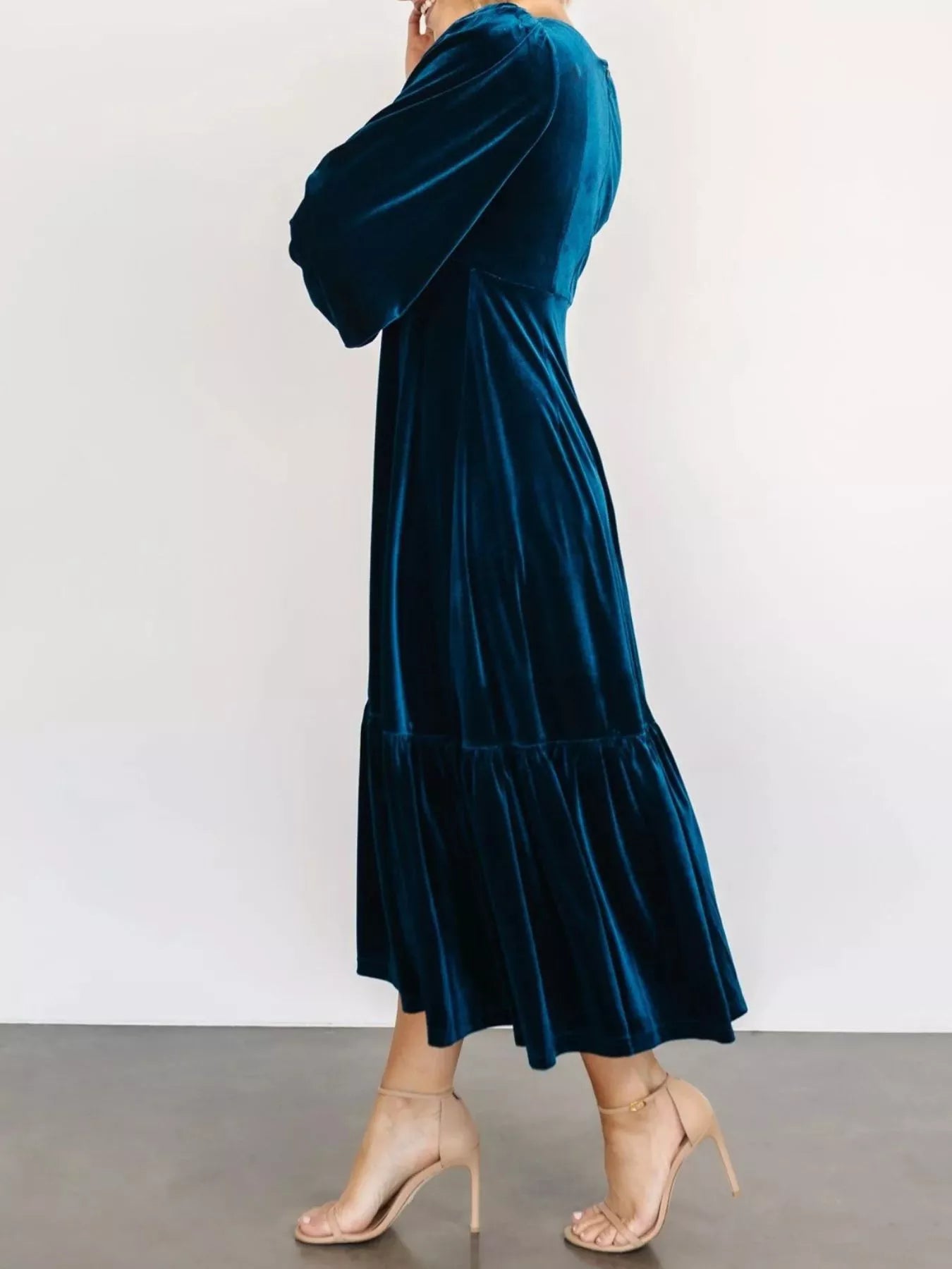 Woman wearing a dark blue velvet midi dress with long sleeves and tiered hem — elegant soft-touch holiday dress from A Whimsical Affair.