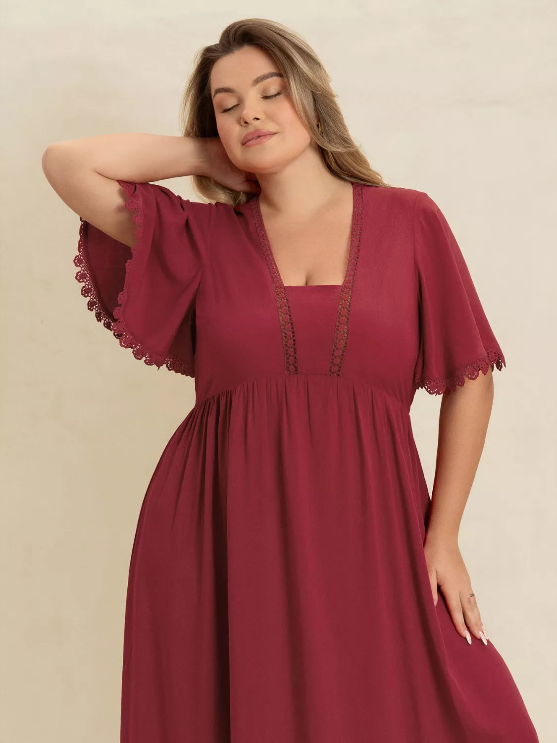 Plus-size woman wearing wine red lace trim maxi dress with flutter sleeves