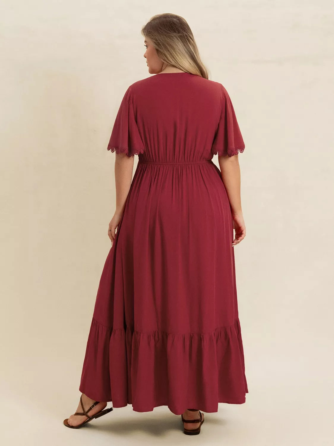 Plus-size woman wearing wine red lace trim maxi dress with flutter sleeves
