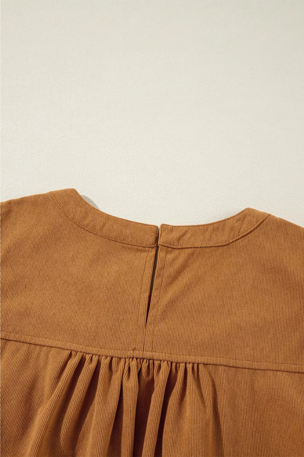 Woman wearing a relaxed long sleeve babydoll dress in warm brown tones with boots