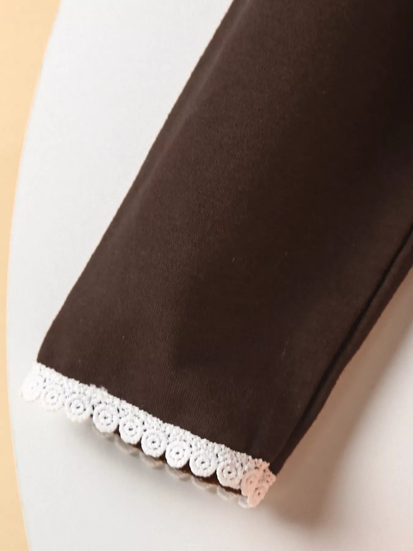 Three-piece baby girl outfit with orange plaid turkey dress, brown cardigan, and matching plaid headband on a beige background with fall leaves.