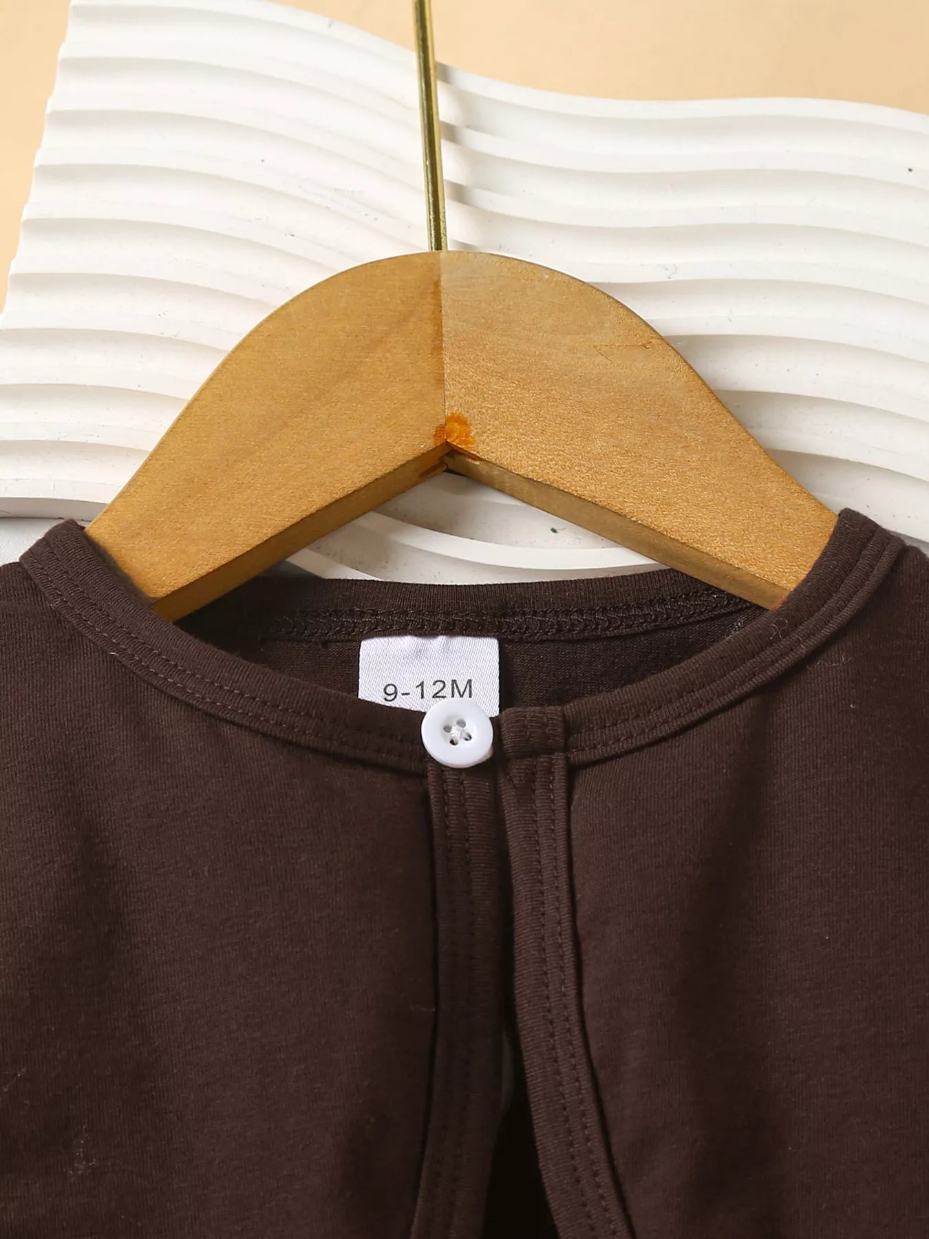 Three-piece baby girl outfit with orange plaid turkey dress, brown cardigan, and matching plaid headband on a beige background with fall leaves.