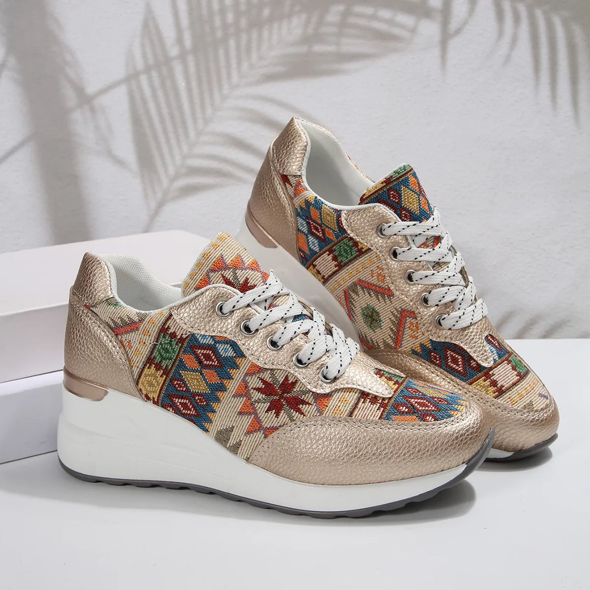 A pair of Aztec Rise Wedge Sneakers with colorful geometric patterns, lace-up design, and hidden wedge heel in cream and khaki color options