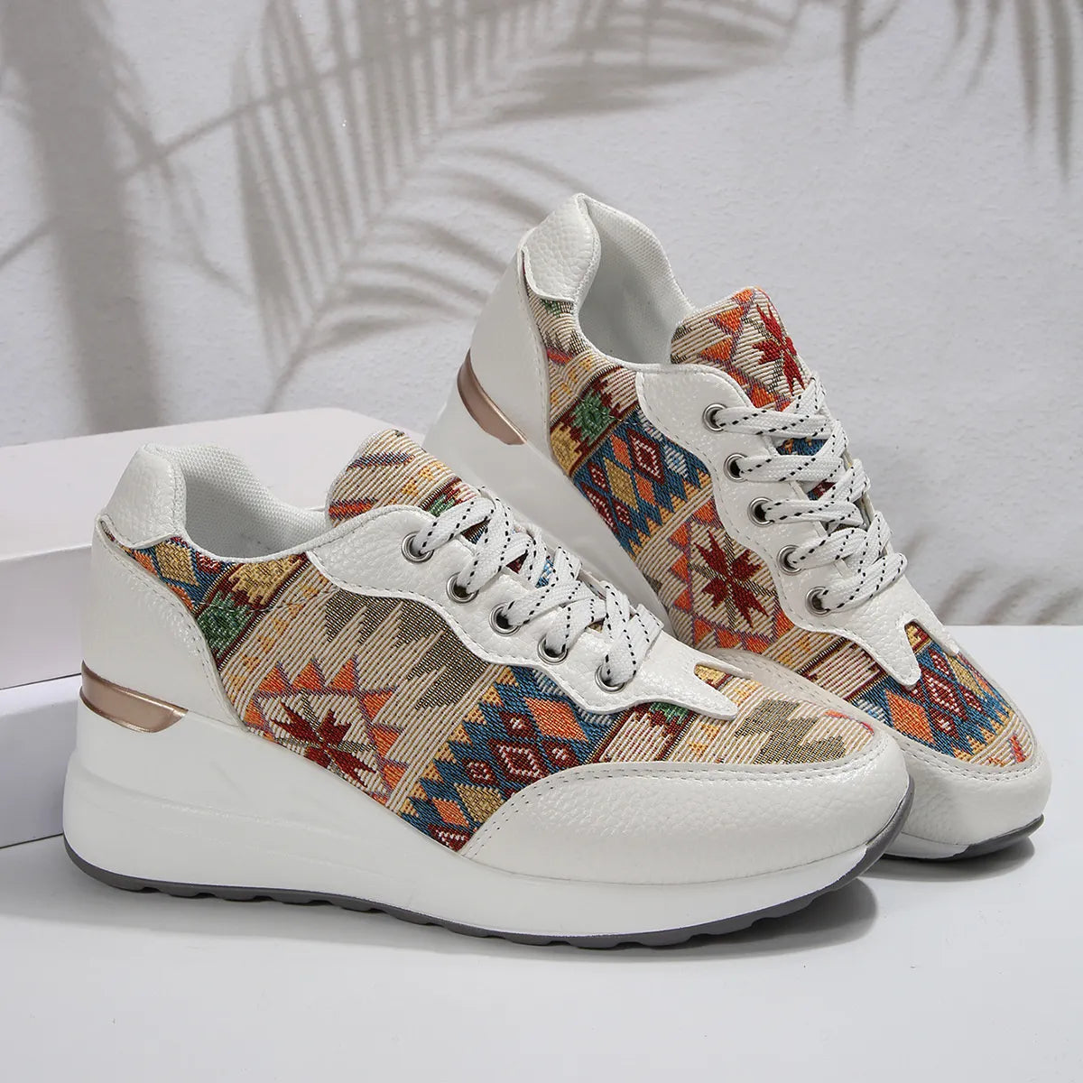 A pair of Aztec Rise Wedge Sneakers with colorful geometric patterns, lace-up design, and hidden wedge heel in cream and khaki color options