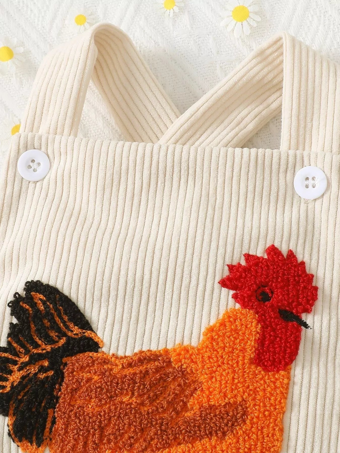 Cream ribbed corduroy baby romper with button straps, snap bottom, and textured chicken appliqué on the front.