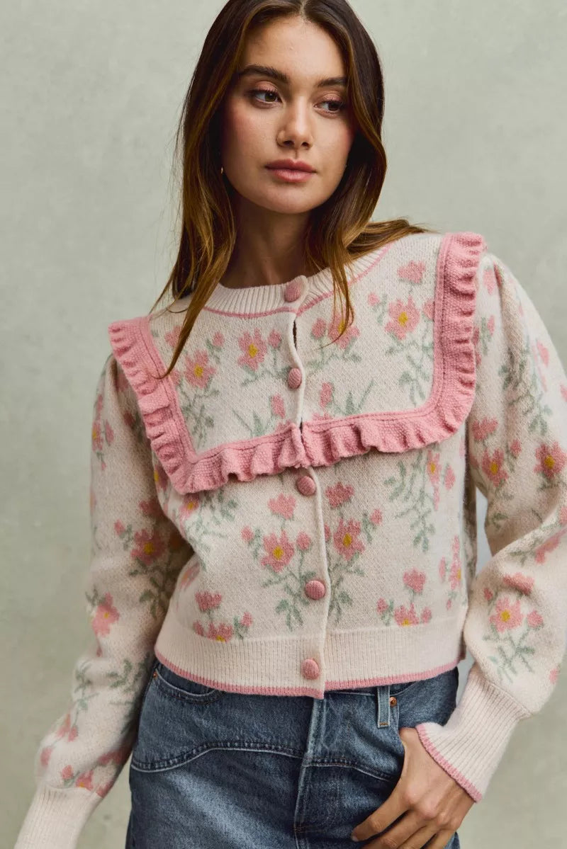 Floral knit cardigan with pink ruffled yoke and covered buttons.