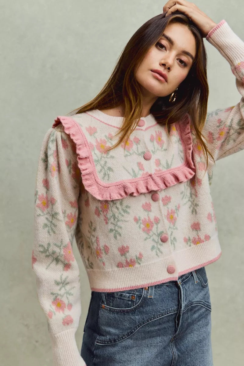 Floral knit cardigan with pink ruffled yoke and covered buttons.