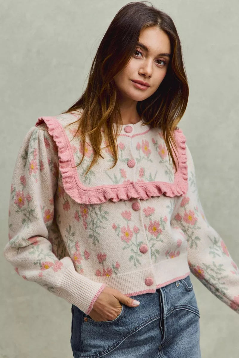 Floral knit cardigan with pink ruffled yoke and covered buttons.