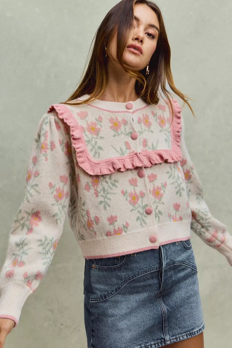 Floral knit cardigan with pink ruffled yoke and covered buttons.