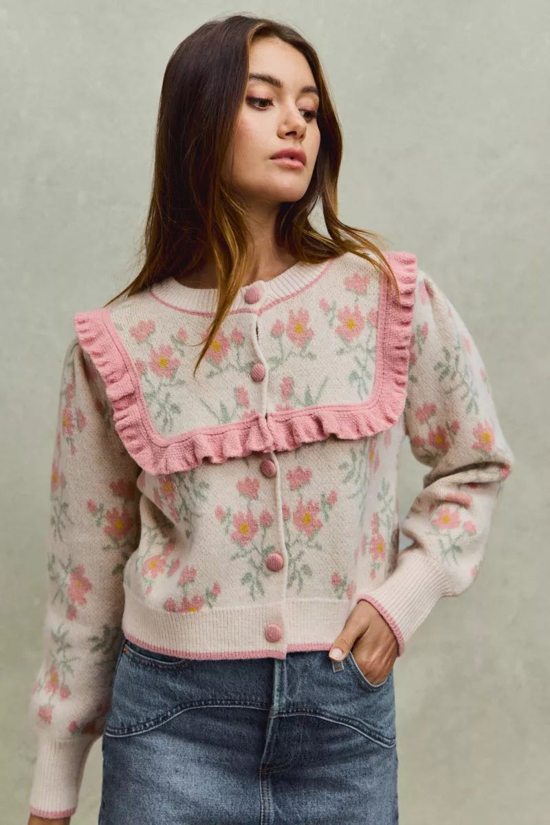 Floral knit cardigan with pink ruffled yoke and covered buttons.