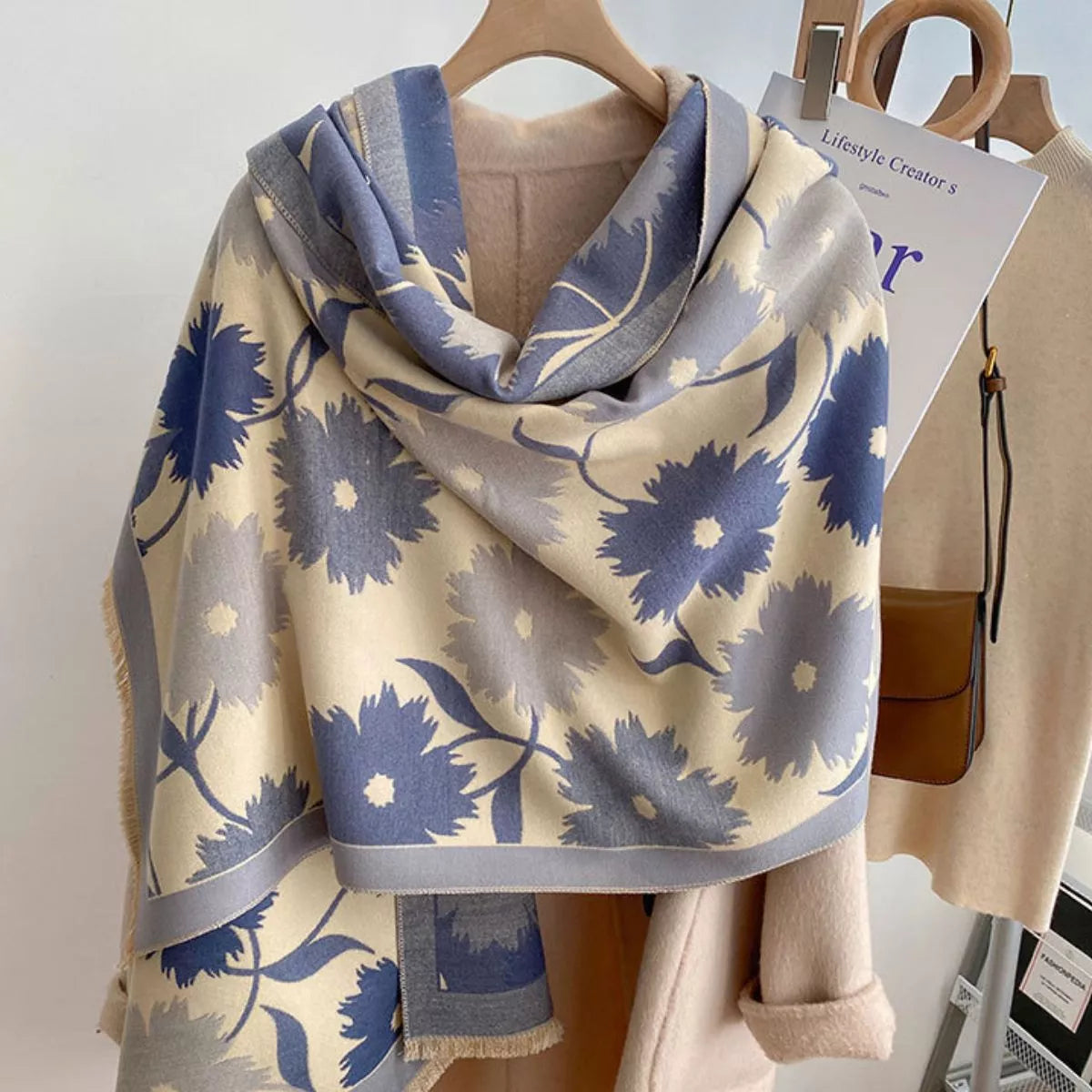 Oversized floral fringe scarf draped over a coat, featuring soft multicolor botanical patterns and lightweight fabric