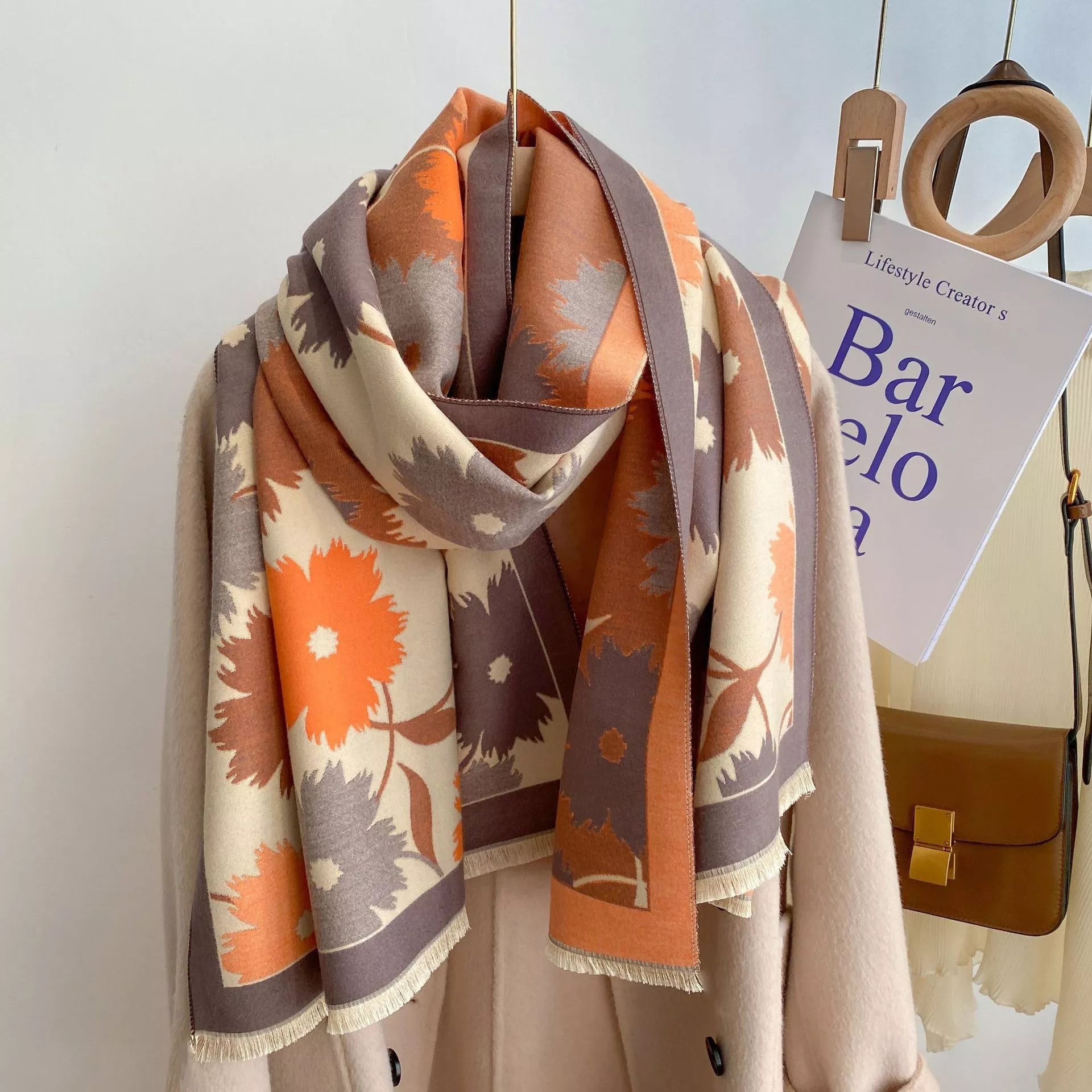 Oversized floral fringe scarf draped over a coat, featuring soft multicolor botanical patterns and lightweight fabric