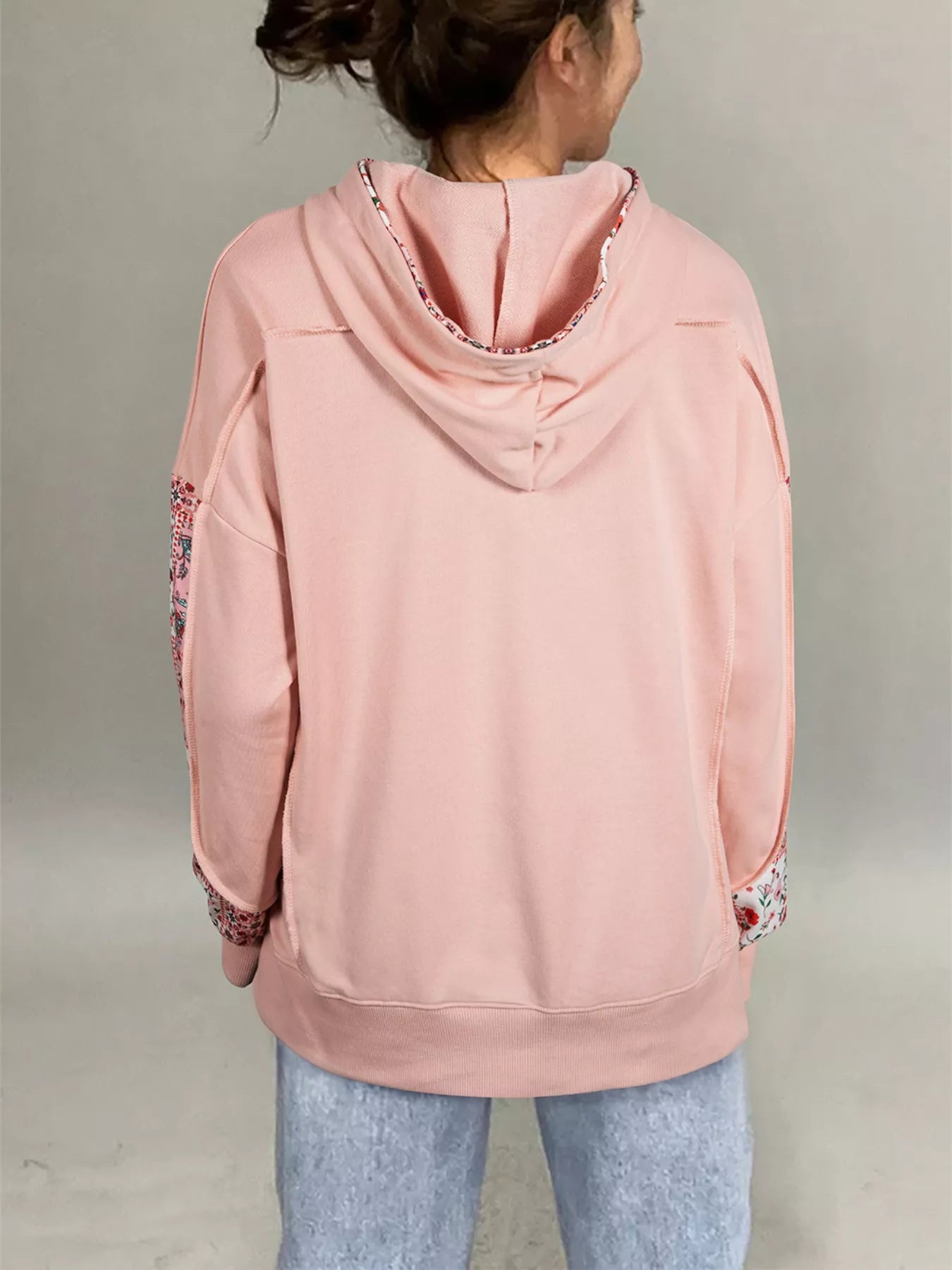 Model wearing Blossom Path Hoodie in dusty pink with floral patchwork details and drawstring hood