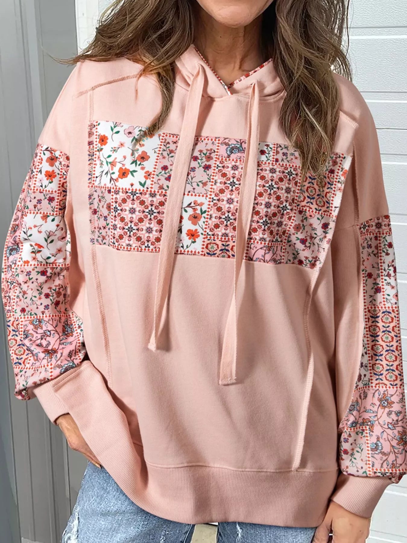 Model wearing Blossom Path Hoodie in dusty pink with floral patchwork details and drawstring hood